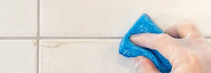 Hand in Handschuh reinigt Fliesen